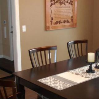 A dining room with a dark wooden table, chairs, and decorative wall art.