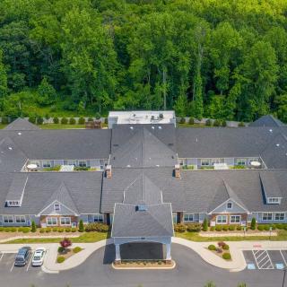 Aerial view of a large building with a parking lot, surrounded by trees.