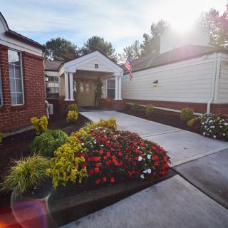 A beautifully landscaped entrance with bright flowers lining the pathway to a building.