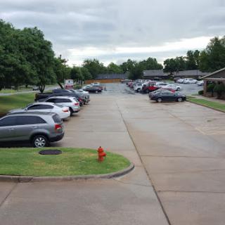 A view of a parking lot with various vehicles parked, set against a cloudy sky.