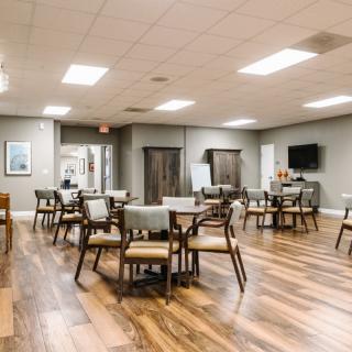 A modern dining area with tables and chairs on a wooden floor.