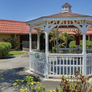 A white gazebo in a landscaped garden setting on a sunny day.