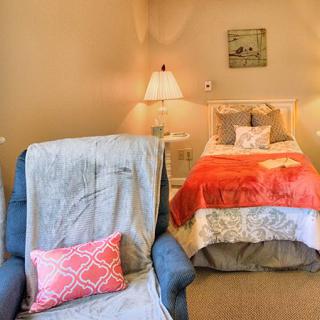 A cozy bedroom setup with a comfy chair and vibrant bedding.