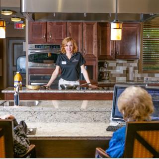A cooking demonstration in a modern kitchen setting with participants observing.
