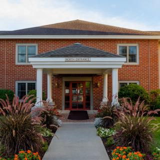 A brick building with a well-landscaped entrance and a pathway leading to the door.
