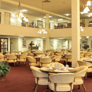 Spacious dining area with multiple tables and chairs, illuminated by chandeliers.
