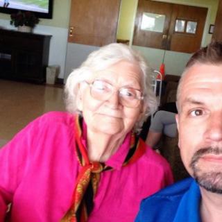 An elderly woman and a man taking a selfie indoors.