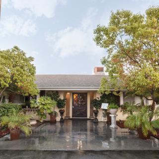 A welcoming house entrance surrounded by lush greenery and potted plants.