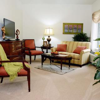 A cozy living room with a sofa, armchairs, and a television.