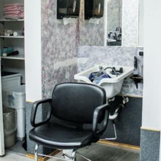 A barbershop interior featuring a chair in front of a wash basin.