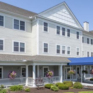 A large, multi-story building with a blue awning and neatly landscaped surroundings.