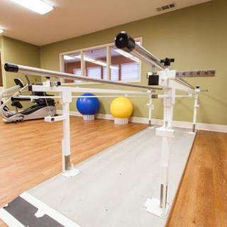 A physical therapy studio equipped with a balance bar and exercise balls.
