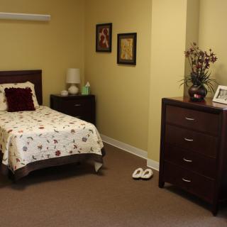 A cozy bedroom with a single bed, dresser, and decorative elements.