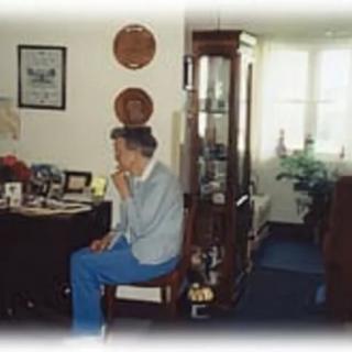 A person sitting in a home environment surrounded by furniture and decor.