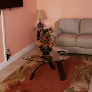 A cozy living room with a glass coffee table, floral arrangement, and a sofa.