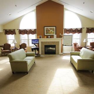 A spacious living room with two sofas facing a fireplace, large windows providing ample natural light.