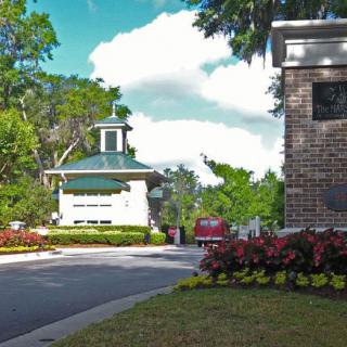 A scenic entrance featuring a gatehouse surrounded by lush landscaping and colorful flowers.