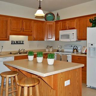 A cozy kitchen with wooden cabinets, a central island, and modern appliances.