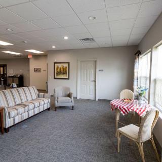 A cozy living room with a sofa, chairs, and a table near large windows letting in natural light.