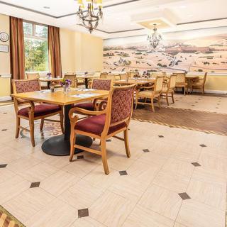 Elegant dining area with neatly arranged tables and chairs, featuring warm lighting and decorative wall art.