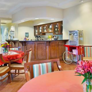 A cozy dining area featuring tables adorned with flowers and a popcorn machine near a wooden kitchen counter.