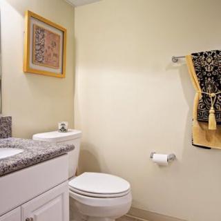 A clean and modern bathroom with a toilet, sink, and decorative towels.