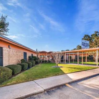 A well-maintained building surrounded by lush greenery and a clear blue sky.