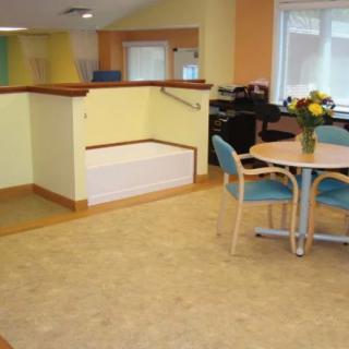 A cozy reception area with a table, chairs, and flowers near a window.
