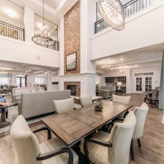 A modern open-concept living and dining area featuring high ceilings, a fireplace, and elegant chandeliers.