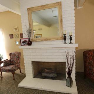 A cozy living room featuring a white brick fireplace with a large mirror above it.