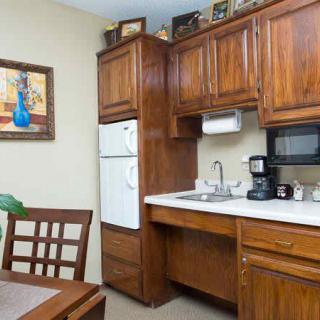 A cozy kitchen corner featuring wooden cabinets, a refrigerator, sink, and countertop appliances such as a microwave and coffee maker.