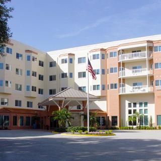 A multi-story residential building with a central entrance and an American flag in front.