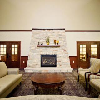 A cozy living room featuring a central stone fireplace, surrounded by sofas and elegant wooden accents.