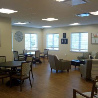 A cozy seating area with tables and chairs, well-lit by natural light from several windows.