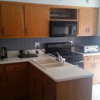 A kitchen with wooden cabinets, a stove, microwave, and a double sink.