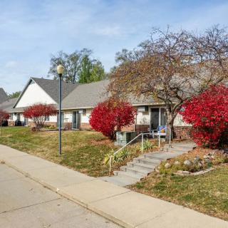 A suburban street with houses and vibrant red bushes in autumn.