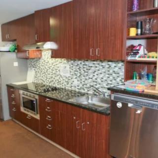 A modern kitchen with sleek wooden cabinets, a tiled backsplash, and stainless steel appliances.