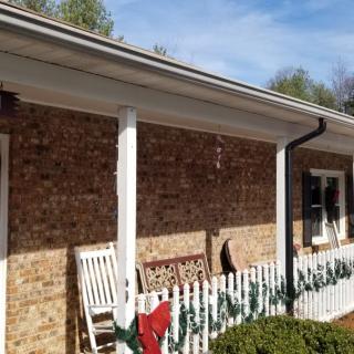 A cozy porch with a brick facade featuring rocking chairs and festive decorations.