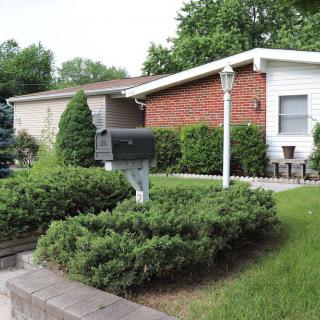 A suburban house with a well-maintained yard featuring bushes and a mailbox.