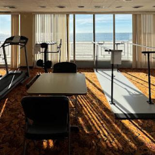 A well-lit fitness area with treadmills and tables, offering a scenic view of the ocean.