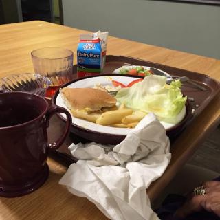 A tray with a sandwich, fries, lettuce, and drinks on a table.