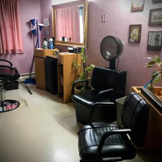 A cozy hair salon with chairs, a mirror, and a hair dryer in the corner.
