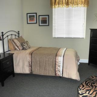 A cozy, well-lit bedroom featuring a neatly made bed, stylish furniture, and decorative accents.
