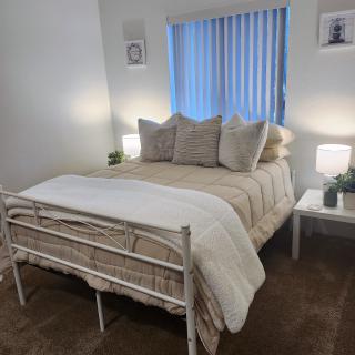 A cozy bedroom with a neatly made bed, pillows, and bedside lamps.