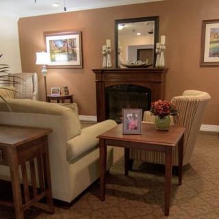 A cozy living room featuring a fireplace, sofa, and coffee table, adorned with art and decor.