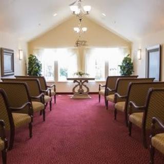 A serene chapel interior with rows of chairs and natural light streaming through large windows.