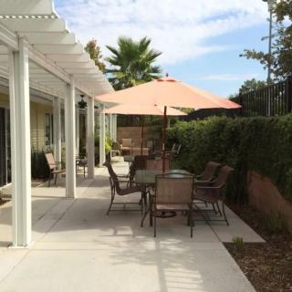 A backyard patio with outdoor furniture and an umbrella providing shade.