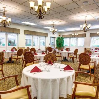 An elegantly set dining room with round tables and chandeliers.