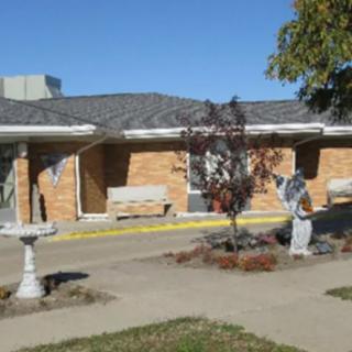 A small brick building with a tree and sculptures outside.