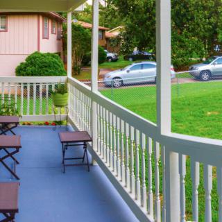 A peaceful suburban porch overlooking a green lawn and parked cars.